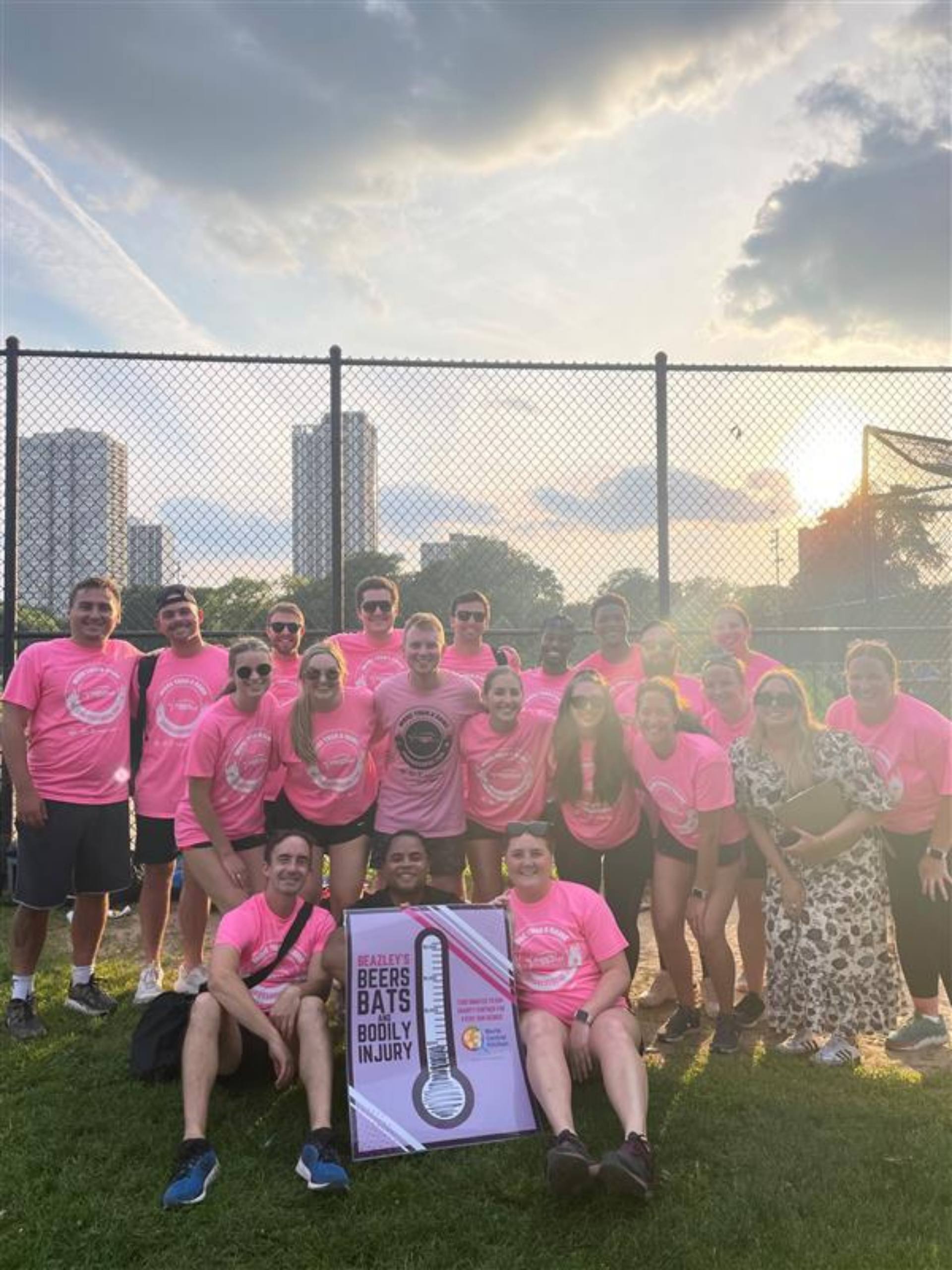 A group of individuals wearing pink shirts smiles and poses together for a photograph.