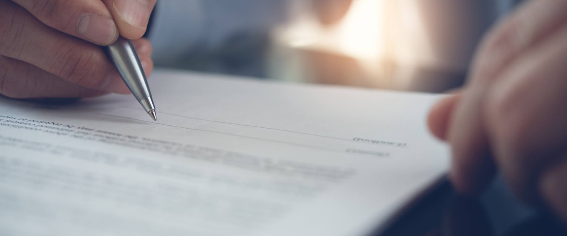 A man engaged in signing a contract with a pen, representing the finalization of an important document.