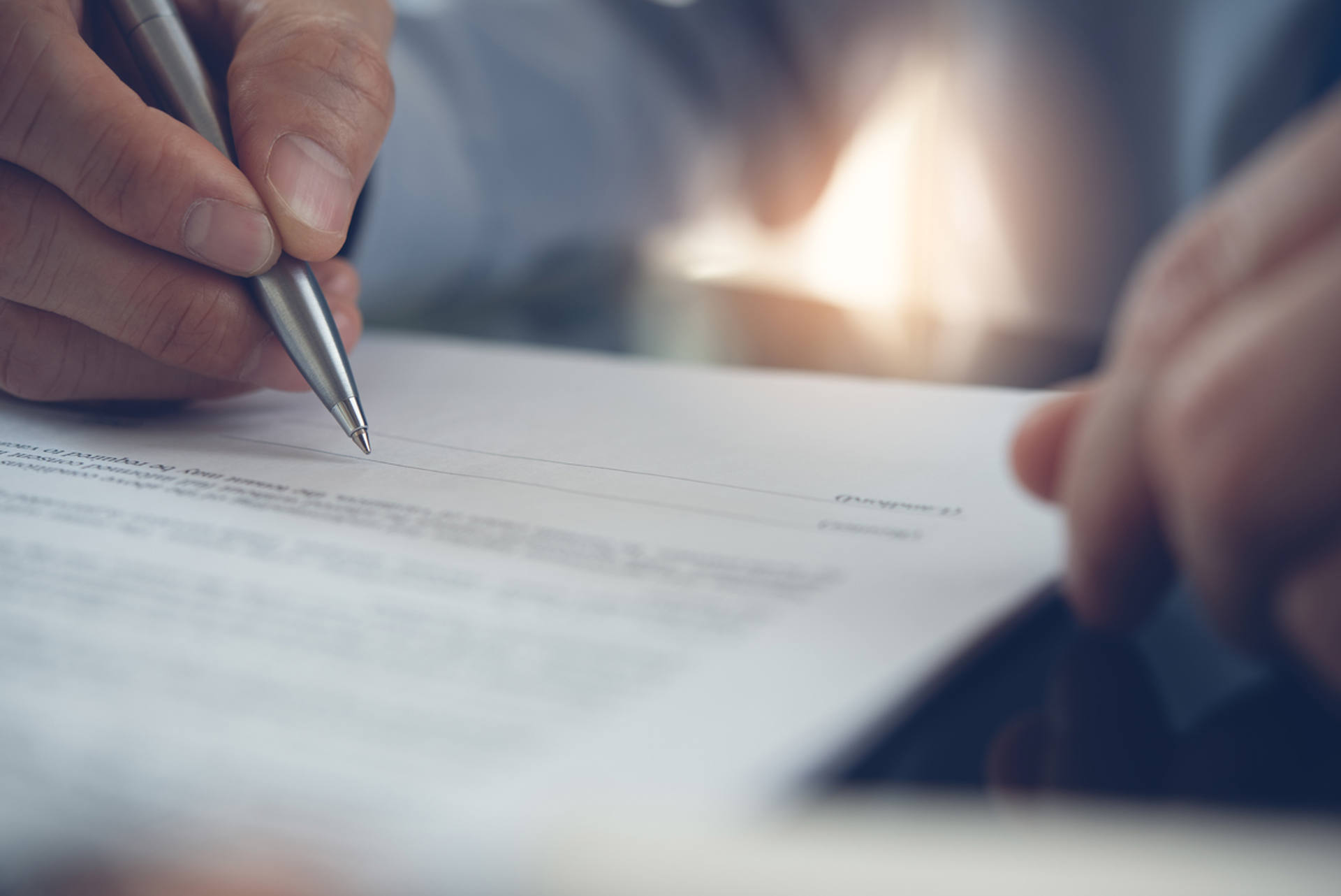 A man engaged in signing a contract with a pen, representing the finalization of an important document.