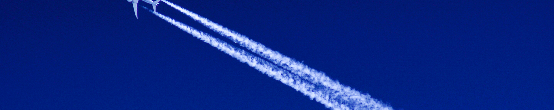 A jet aircraft ascends in the sky, creating a visible contrail as it moves swiftly through the atmosphere.