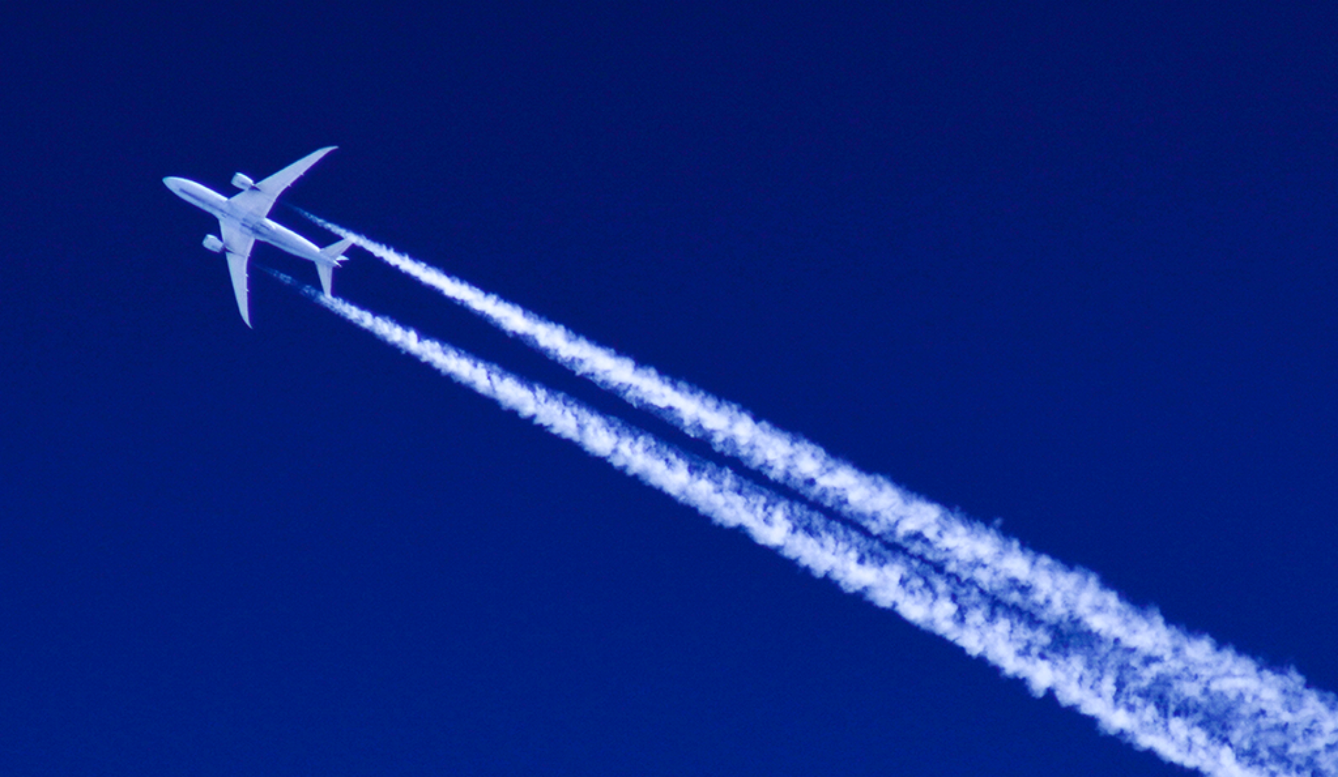 A jet aircraft ascends in the sky, creating a visible contrail as it moves swiftly through the atmosphere.